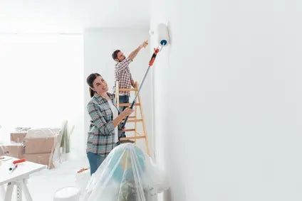 Paar streicht gemeinsam die Wände einer Wohnung