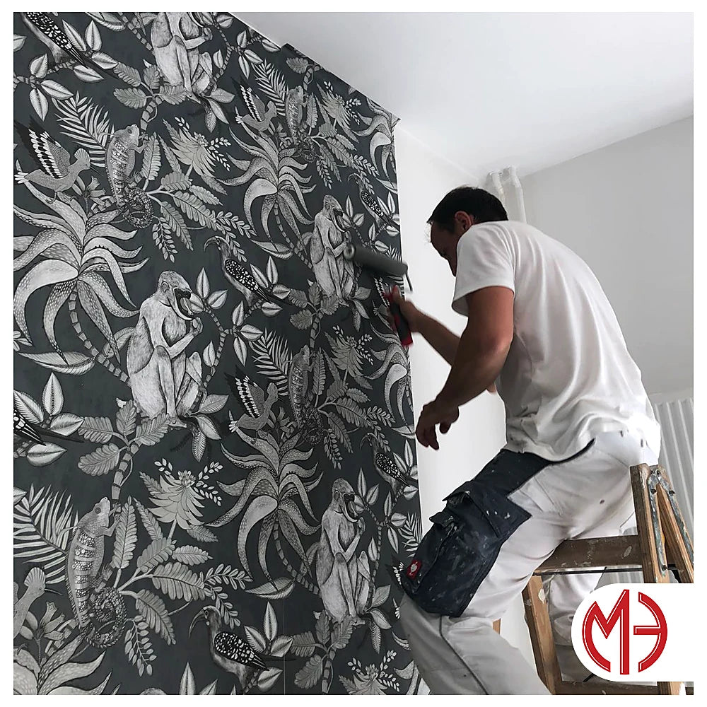 Maler bei Tapezierarbeiten mit einer dunklen floralen Mustertapete